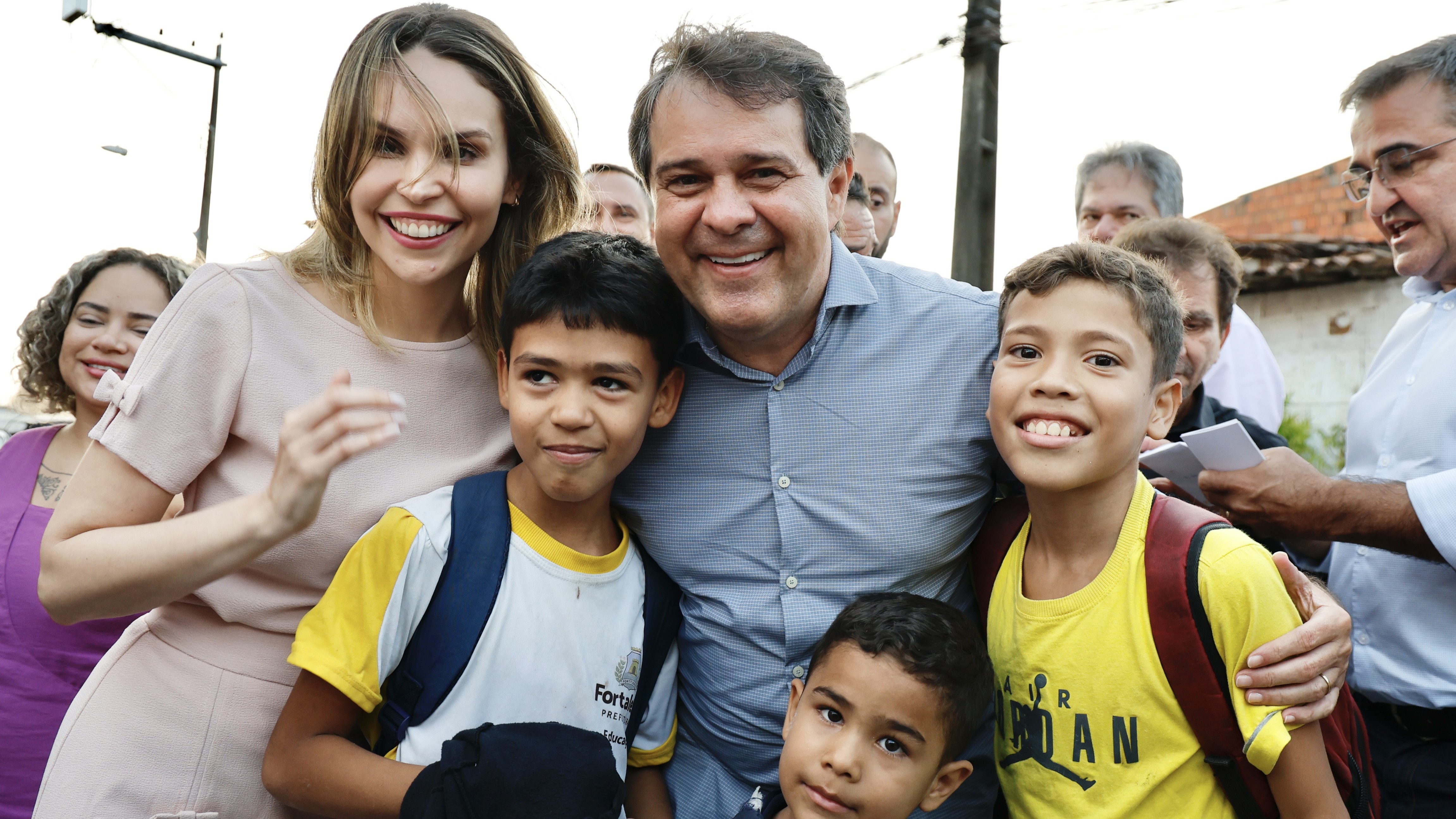 prefeito evandro e vice-prefeita gabriella posam para foto abraçando algumas crianças